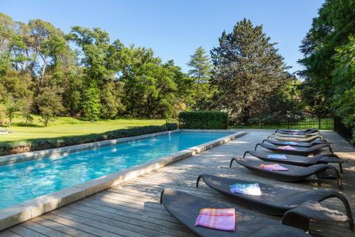 a row of chaise lounge chairs next to a swimming pool at Château Mentone in Masseboeuf
