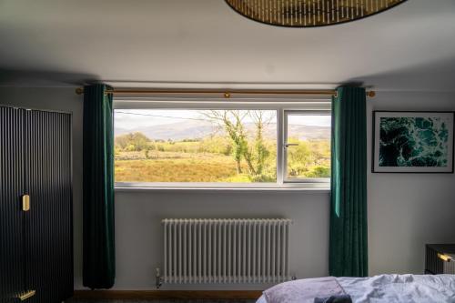 1 dormitorio con ventana con cortinas verdes y radiador en Plas Coch, Snowdon Views with Large Garden, en Caernarfon