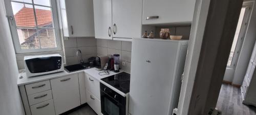 Il comprend une cuisine équipée d'un réfrigérateur blanc et d'une cuisinière. dans l'établissement 45 m2 au Centre Ville - Les bougies, à Corbeil-Essonnes