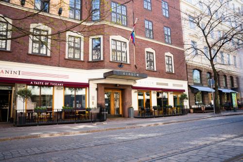 ein Gebäude in einer Stadtstraße mit Tischen und Stühlen in der Unterkunft Hotel Klaus K in Helsinki