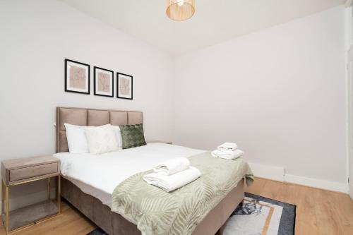een slaapkamer met een bed met witte lakens en handdoeken bij 2 bedroom flat near Tottenham Hotspur Stadium in Londen