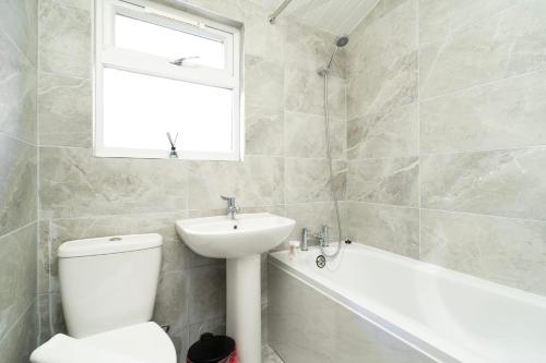 een badkamer met een toilet, een wastafel en een bad bij 2 bedroom flat near Tottenham Hotspur Stadium in Londen
