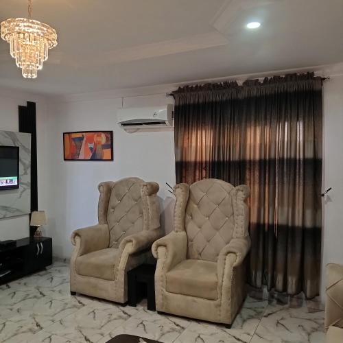 2 sillas en una sala de estar con lámpara de araña en J Lounge en Ikorodu