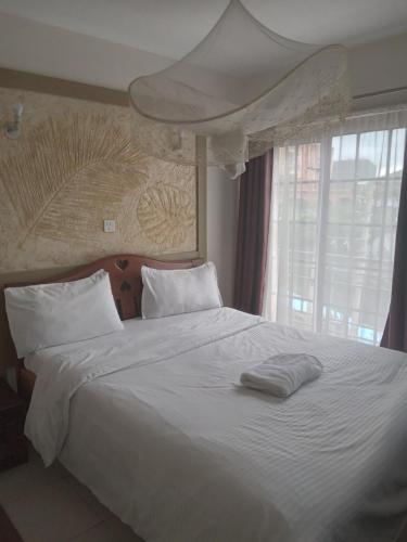 Mvuli suites في نيروبي: غرفة نوم بسرير أبيض مع نافذة كبيرة