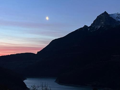 a mountain with the moon in the sky at sunset at Hôtel du tilleul in Corps