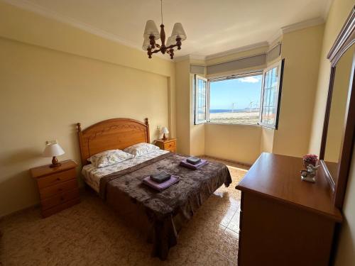 a bedroom with a bed and a desk and a window at P&A Apartment in Playa del Burrero