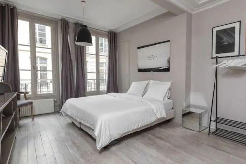 - une chambre blanche avec un grand lit et des fenêtres dans l'établissement Saint-Honoré Luxurious 2 Bedrooms apartment 120m2, à Paris