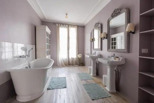 La salle de bains est pourvue d'une baignoire, de 2 lavabos et d'un miroir. dans l'établissement Saint-Honoré Luxurious 2 Bedrooms apartment 120m2, à Paris