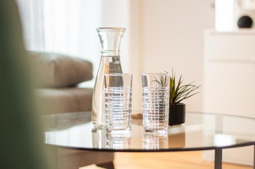 巴塞爾的住宿－Special EiNSTEiN II Apartment Basel, Messe Kleinbasel 10-STAR，玻璃瓶和桌子上的两杯