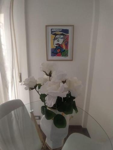 een witte vaas met witte bloemen op een tafel bij Appartamento giardino in Rapallo