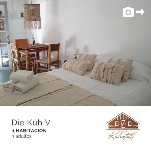 a bedroom with a bed with pillows and a table at Casa Kuhstall in La Cumbrecita