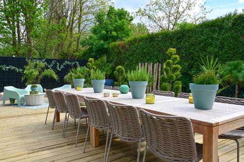 a table and chairs on a deck with plants at Extraordinaire Villa 5 étoiles 12 personnes 7 min Lille in Marcq-en-Baroeul