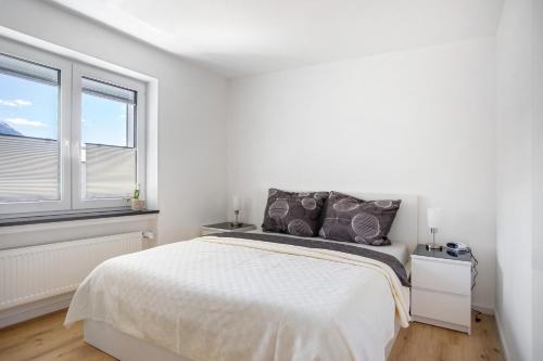 a white bedroom with a bed and two windows at Im Spatzennest in Inzell