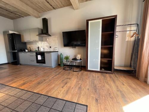 a living room with a kitchen and a hard wood floor at Barwny Zakątek in Augustów