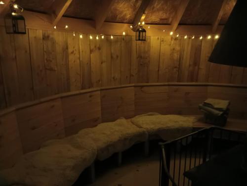 a room with a long couch in a room with wooden walls at Lucker mill shepherds huts in Lucker