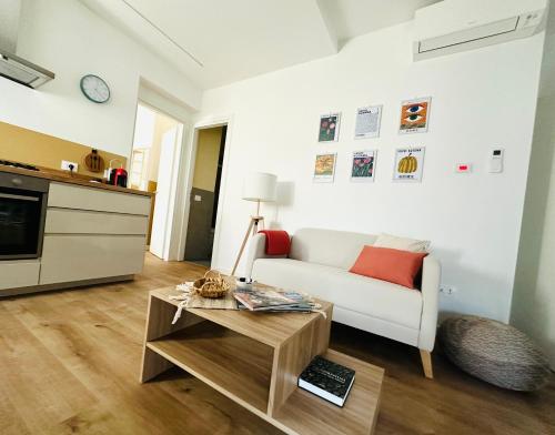 ein Wohnzimmer mit einem weißen Sofa und einem Tisch in der Unterkunft Nuovo appartamento Castiglione in Castiglione della Pescaia