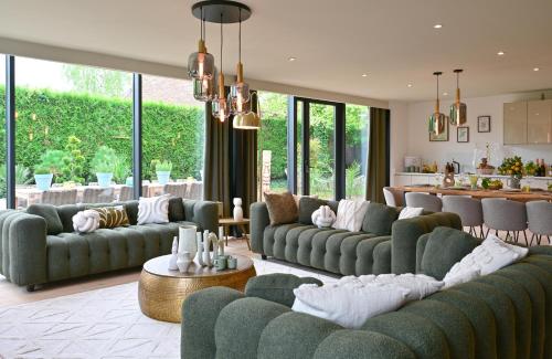 a living room with green couches and a kitchen at Extraordinaire Villa 5 étoiles 12 personnes 7 min Lille in Marcq-en-Baroeul