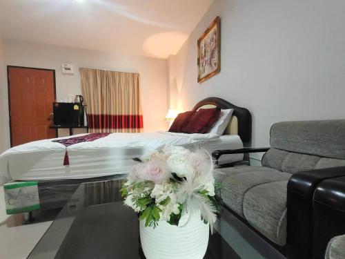 a hotel room with a bed and a table with flowers at ห้องพักนครราชสีมาใกล้เซ็นทรัล The Rich Room in Ban Pra Dok