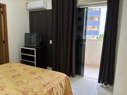 Schlafzimmer mit einem Bett, einem TV und einem Fenster in der Unterkunft THERMAS DO BANDEIRANTE in Caldas Novas