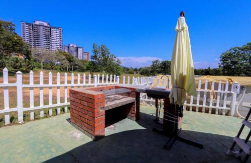 a brick table and an umbrella next to a fence at Mushroom Villa Best homestay in Kampong Alor Gajah