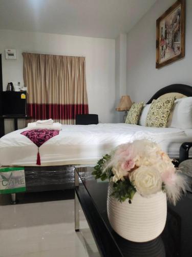 a bedroom with a bed and a table with flowers at ห้องพักนครราชสีมาใกล้เซ็นทรัล The Rich Room in Ban Pra Dok