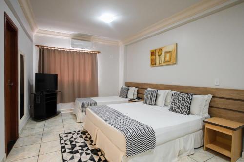 una camera d'albergo con due letti e una televisione di Havana Palace Hotel a Uberaba
