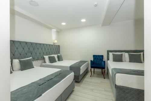 a bedroom with two beds and a blue chair at Bursa Grand Family HOTEL in Bursa
