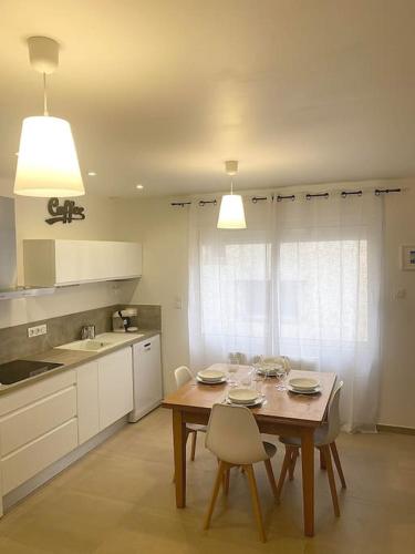 une cuisine avec une table en bois, des chaises, une table et une table dans l'établissement Appartement au cœur du Grau, au Grau-du-Roi