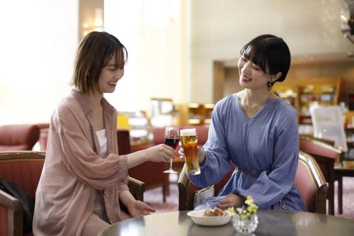duas mulheres sentadas numa mesa com copos de vinho em 有馬 瑞宝園 em Kobe