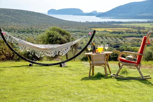 a hammock and a table and chairs on a field at Residenza alla Collina & Romantic SPA in Porto Conte