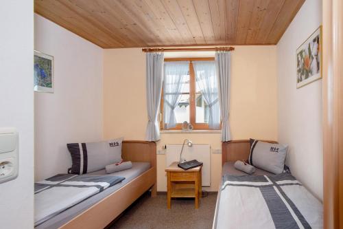 two beds in a small room with a window at Ferienhof 'beim Wendlar' in Bad Hindelang