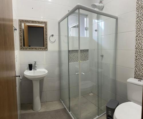 a bathroom with a glass shower and a sink at Casa Cataratas in Foz do Iguaçu