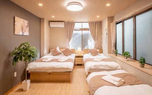 a room with three beds and a potted plant at New open 和風住宅 東中野駅 大久保駅徒歩圈内 新宿駅まで電車5分渋谷銀座東京近い 荷物預かります in Tokyo