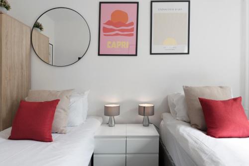 a room with two beds with red pillows and a mirror at Studio 2- Archway Station in London