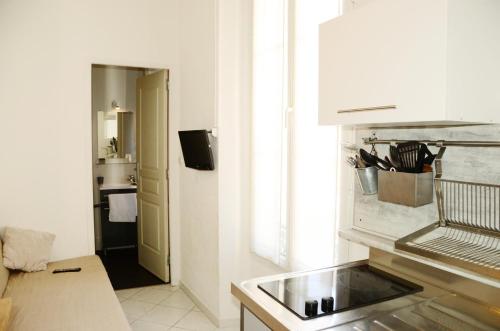 biała kuchnia ze zlewem i oknem w obiekcie Hôtel L'Oustaou w mieście Le Lavandou