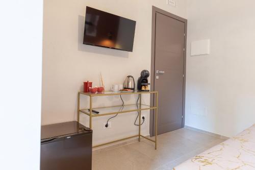 a room with a tv on the wall and a shelf at Malva Rooms in Agrigento
