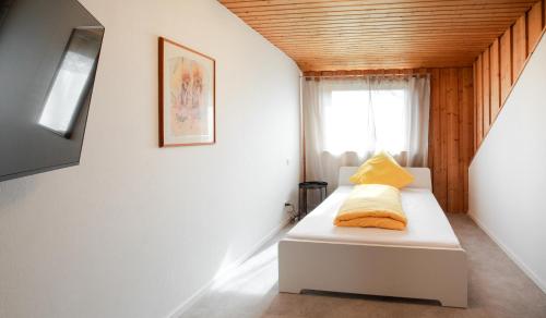 sypialnia z białym łóżkiem z żółtymi poduszkami w obiekcie Ferienwohnung Wäller Fernblick w mieście Westerburg