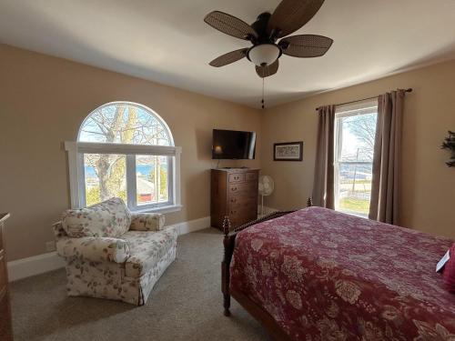 a bedroom with a bed and a chair and a ceiling fan at Lady Mary Angeline in Saint Ignace