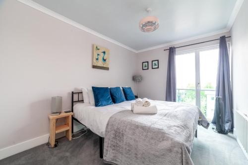 um quarto com uma cama com almofadas azuis e uma janela em Stylish Chic Retreat: 1-bed, Near Canary Wharf em Londres