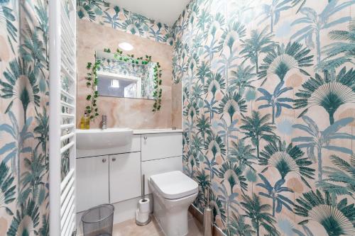 a bathroom with a toilet and tropical wallpaper at Stylish Chic Retreat: 1-bed, Near Canary Wharf in London