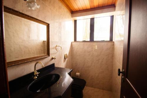 uma casa de banho com um lavatório, um espelho e um WC. em Chacara totalmente equipada em Juiz de Fora MG em Juiz de Fora