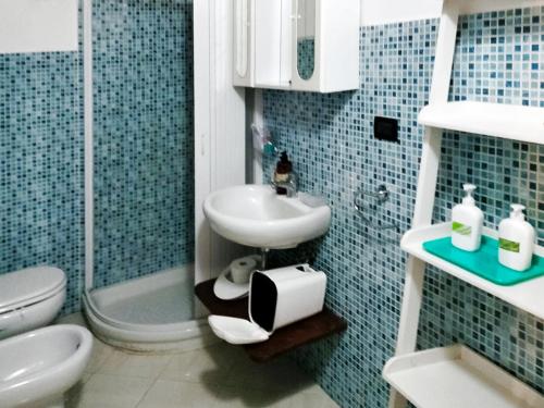 a blue tiled bathroom with a sink and a toilet at Ai 4 gatti in Asciano