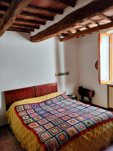 a bedroom with a bed with a colorful quilt on it at Ai 4 gatti in Asciano
