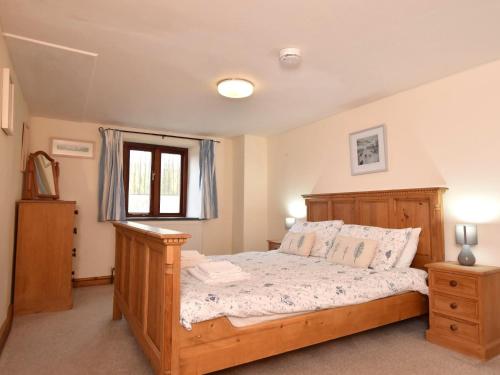 a bedroom with a wooden bed and a window at 4 Bed in Bude CORYS in Morwenstow