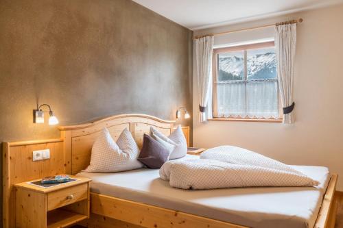 Un dormitorio con una cama con almohadas blancas y una ventana en Ronsolhof Ortler, en Siusi