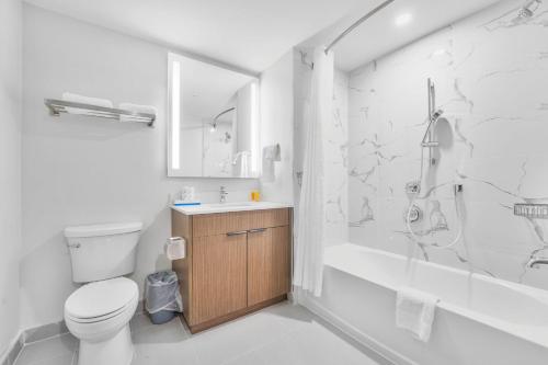 a white bathroom with a toilet and a shower at Skye Residences in Toronto