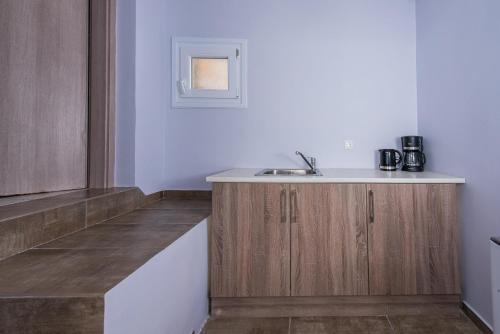 a kitchen with wooden cabinets and a sink at GIN Wellness Hotel in Pyrgos