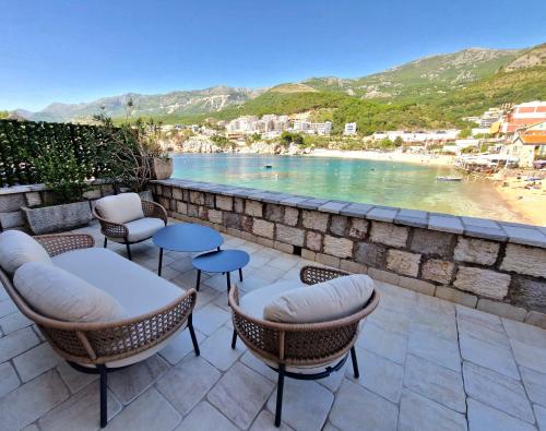 a patio with chairs and tables and a view of a beach at Kazanegra Exclusive Apartments in Sveti Stefan