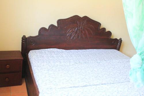 a bed with a wooden headboard in a bedroom at Kiriri SYMPA Home in Bujumbura