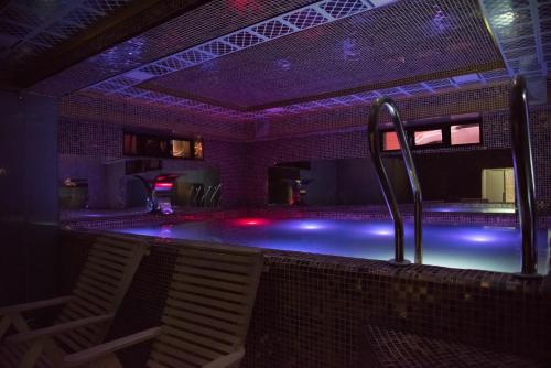 杜尚別的住宿－HOTEL DIOR，黑暗的房间里,游泳池配有椅子